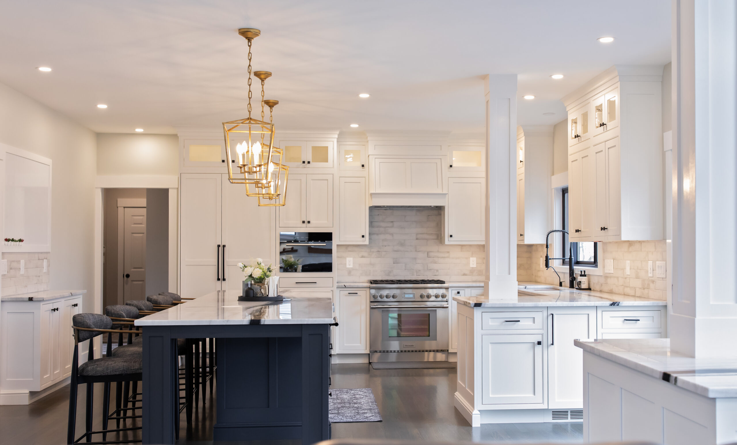 Wide angle photo of a kitchen island, kitchen lighting, kitchen appliances, and interior design performed by Emily's Interiors Kitchen showroom in Shrewsbury Massachusetts